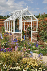 Small greenhouse in flower lovers garden.