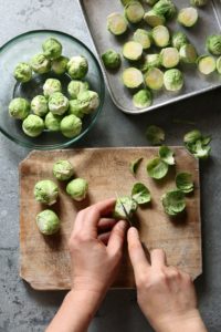 Hands cutting brussels sprouts on a chopping board